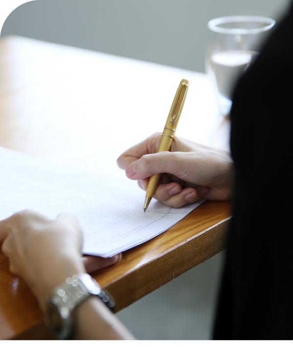 Someone holds a gold pen to a piece of paper